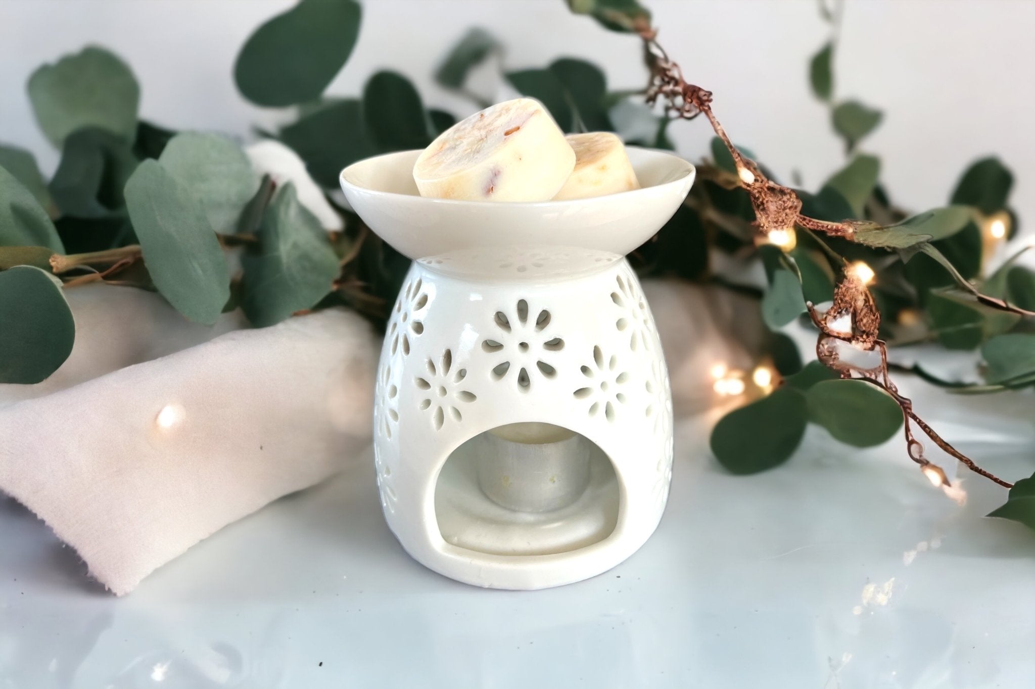 a white oil burner with soy wax melt pods and a decorative eucalyptus plant